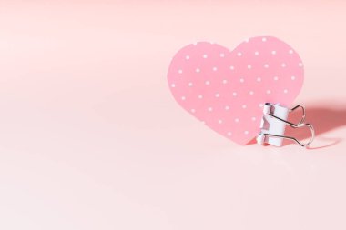 Pembe arka planda ataçta kağıt bir kalp. Kart, Sevgililer Günü 'nde, doğum gününde, Anneler Günü' nde el yapımı tebrikler..