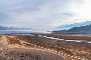 Sisli dağlar ve gölün mavimsi siluetleri. Güzel dağ manzarası. Orto-Tokoy rezervuarı ve Kırgızistan 'daki Chu nehri..