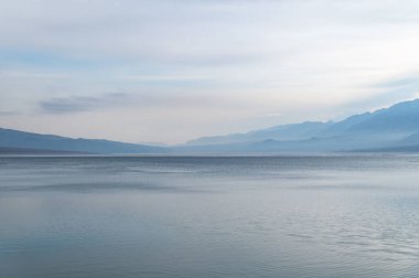 Sisli dağların ve gölün siluetleri. Güzel dağ manzarası. Kırgızistan 'da kışın Orto-Tokoy rezervuarı.
