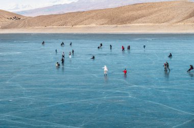 Ara-Kol Gölü, Naryn Bölgesi, Kırgızistan - 5 Ocak 2024: Birçok insan donmuş gölde kayarak kızak yaptı. Kış tatillerinde etkinlik. Ara-Kol Gölü 'nün donmuş manzarası.