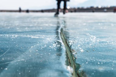 A man skates on a frozen lake with cracks in the ice. Selective focus. Place for text. clipart