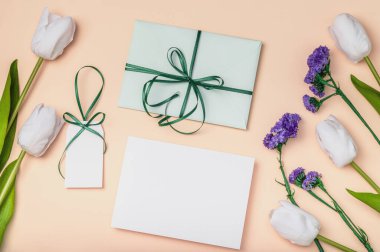 Yeşil zarf, boş etiket ve beyaz laleli şeftali arka planda bir kart. Paskalya, Uluslararası Kadınlar Günü, Anneler Günü, Sevgililer Günü ve Doğum Günü için tebrikler..