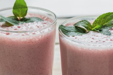 Nane yapraklarıyla süslenmiş taze çilekli milkshake. Seçici odak.