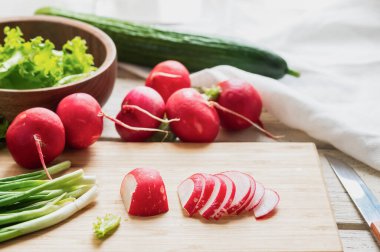 Turp, salatalık ve bitkilerden oluşan taze bahar salatası. Mutfak tahtasının üzerinde doğranmış turplar..