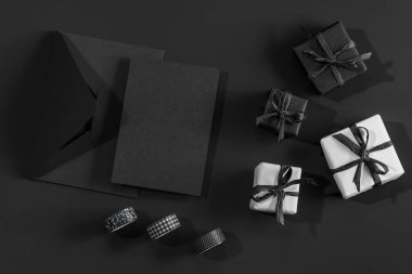 Siyah arkaplanda beyaz ve siyah hediye kutuları ve metin için yeri olan siyah bir zarf.. 