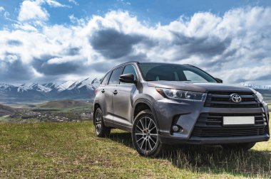 Bishkek, Kırgızistan - 9 Nisan 2023: Toyota Highlander karlı dağların arka planına karşı bir dağ yamacında duruyor.