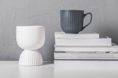 Gri kupa, beyaz vazo ve kitaplarla dolu bir hayat. İskandinav iç mimarisi.