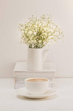 Kahve, bir buket çingene ve beyaz bir masanın üzerinde bir yığın kitap. Sıcak kahvaltı..