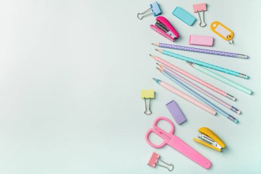 Açık mavi arka planda pembe tonlarda kırtasiye malzemesi. Okula geri dön..
