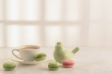 Coffee, macaroons and a porcelain figurine of a bird on a white table. Cozy breakfast. clipart