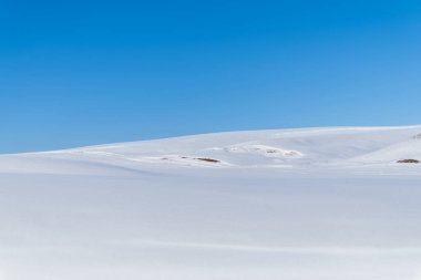 Beyaz karla kaplı tepeler ve mavi gökyüzünün aksine. Dağlarda güneşli bir kış günü.