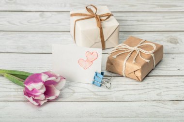Lale, çekilen kalpler ve tahta arka planda hediye kutuları olan kart. Anneler Günü, Sevgililer Günü, Doğum günü ve Kadınlar Günü 'ne selamlar..
