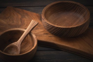 Eski ahşap kesme tahtasının üzerinde el yapımı ahşap kaseler ve kaşıklar. Seçici odak