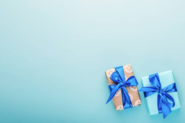 Açık mavi arka planda saten mavi fiyonklu hediye kutuları. Tatil hediyeleri..
