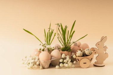 Wooden Easter bunny with a basket of eggs, a container with eggs and sprouted grass. Easter background, greeting card. clipart