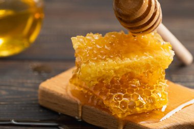 Tahta kesme tahtasının üzerinde bal peteği olan taze altın bal, seçici bir odak. Organik gıda ya da alternatif tıp konsepti.