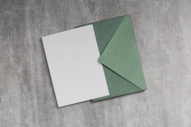 Tebrik kartı modeli, düğün davetiyesi. Beton zemin üzerinde boş form olan yeşil zarf.