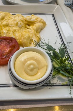 Tereyağı, çırpılmış yumurta, beyaz tabakta mikro yeşiller. Geleneksel kahvaltı.