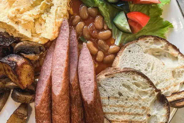 Geleneksel İngiliz kahvaltısı sosis, çırpılmış yumurta ve yakın plan fasulye..