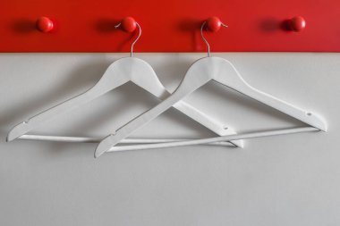 Tahta beyaz askılar, beyaz bir duvara asılı kırmızı ahşap duvar askıları (kancalar).