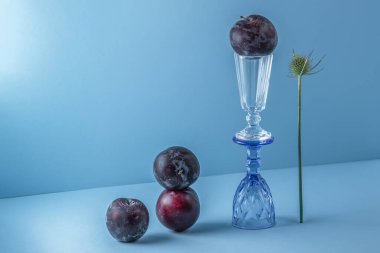 Mavi arka planda olgun erikler ve cam bardaklarla dolu bir hayat.