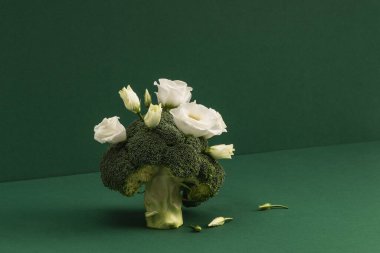 Yeşil arka planda brokoli ve beyaz Eustoma çiçekleriyle yaratıcı natürmort yaşam.