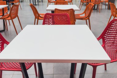 Yemek katında kırmızı sandalyeler ve beyaz masalar. Seçici odak.