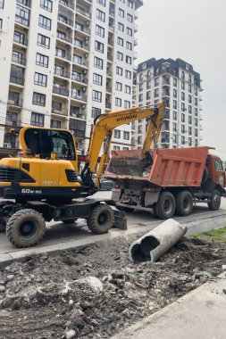 Bişkek, Kırgızistan - 9 Nisan 2025: Bir kazıcı yol onarımı sırasında bir çöp kamyonuna toprak yüklüyor.