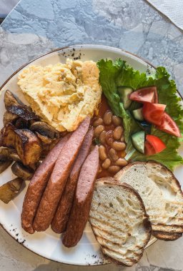 Geleneksel İngiliz kahvaltısı sosis, çırpılmış yumurta ve fasulye beyaz tabakta..