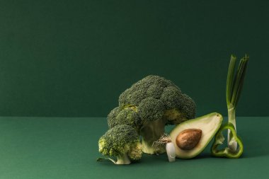 Yeşil arka planda brokoli, avokado ve yeşil soğanlı yaratıcı sebze..