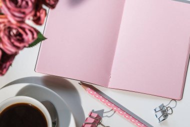 Pembe defter ve bir fincan kahve, çalışma alanı.