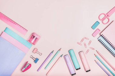 Düz kompozisyon, okul malzemeleriyle birlikte pembe arka planda pastel renklerde. Pembe, eflatun çalışma kitapları ve defterler. Okulun ilk günü, öğretmenler günün kutlu olsun..