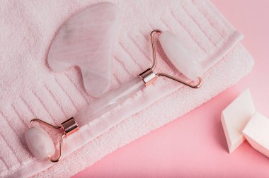Pembe havlunun üzerinde gül kuvars masaj silindiri. Seçici odaklanma. Doğal güzellik konsepti.