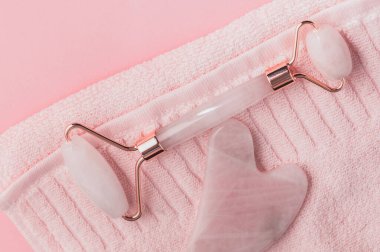 Pembe Gua Sha Yüz Masaj Aletleri. Pembe arka planda gül kuvars yeşim taşı. seçici odak.
