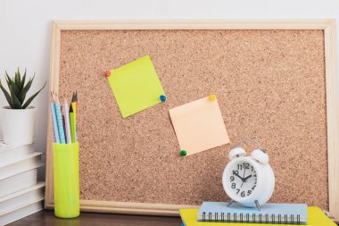 Çalışma alanı beyaz kitaplar, kalem tutacağı, saat ve mantar kapaklı notlar. Okula, üniversiteye, üniversiteye. Okulun ilk günü kutlu olsun. Öğretmenler günün kutlu olsun..