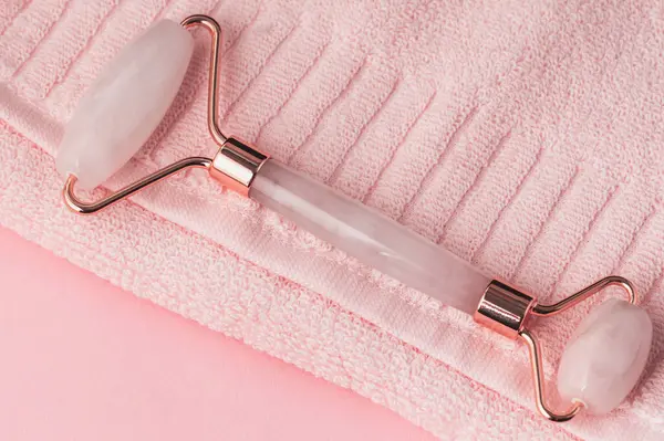Pembe Gua Sha Yüz Masaj Aletleri. Pembe havlunun üzerinde gül kuvars yeşim taşı. Seçici odak.