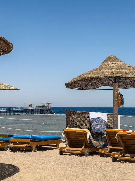 Saman plajı şemsiyeleri ve Mısır 'ın Sharm el-Sheikh sahilindeki iskele. Rahatlamış yaz tatili ve seyahat kavramı..