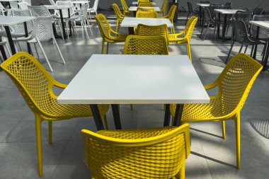 Yemek katında beyaz masa ve sarı plastik sandalyeler. Seçici odak.