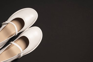 Siyah arka planda fotokopi alanı olan bir çift beyaz ayakkabı. Minimalizm ve basitlik kavramı.