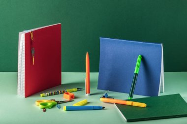 Fotokopi alanı olan yeşil bir arkaplan üzerine not defterleri, kalemler ve diğer okul sayfaları.