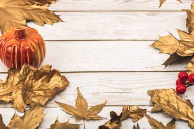 Hafif ahşap zemin üzerinde altın bir çerçeve şeklinde altın yapraklar, kırmızı böğürtlen, balkabağının seramik formu. Sonbahar tatili ve altın sonbahar konsepti.