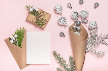 Noel arkaplanı, kartpostal, tebrikler. İçinde cam Noel ağacı topları, zarf ve pembe arka planda hediye paketi olan el işi koni..
