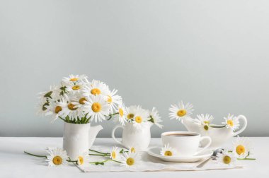 Sabah kahvesi ve beyaz papatyalı üç seramik sürahi. Yaz çiçeği havası. Boşluğu kopyala.