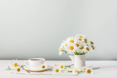 Sabah kahvesi ve beyaz papatyalı seramik sürahi. Yaz çiçeği havası. Boşluğu kopyala.