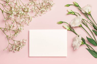Hassas beyaz Eustoma ve çingene çiçekleri ve pembe arka planda boş bir kart. Düz kompozisyon. Kartpostal, davetiye