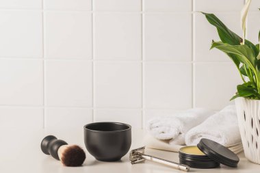 Banyodaki beyaz bir masanın üzerine aksesuar ve beyaz havlular. Erkeklerin kişisel bakım konsepti..