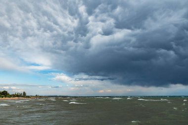 Issyk-Kul 'da fırtına var. Fırtına dalgaları, rıhtım ve sahil manzarası.