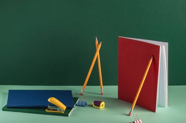 Yeşil arka planda fotokopi alanı olan okul kağıtları. Sarı kalemler ve renkli defterler. İş yeri organizasyonu. Okul konseptine dönelim..