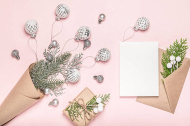 Noel arkaplanı, tebrik kartı. İçinde cam gümüş Noel ağacı topları, zarf ve pembe arka planda hediye paketi olan koni çantası..