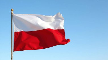 Bir Polonya bayrağı açık mavi gökyüzüne karşı rüzgarda gururla dalgalanıyor. Canlı kırmızı ve beyaz renkler ulusal gururu simgeliyor, birlik ve miras duygusunu çağrıştırıyor..